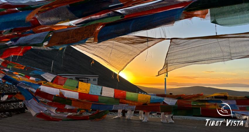 Warm sunset over Namtso Lake with prayer flags fluttering at Nagen La Pass