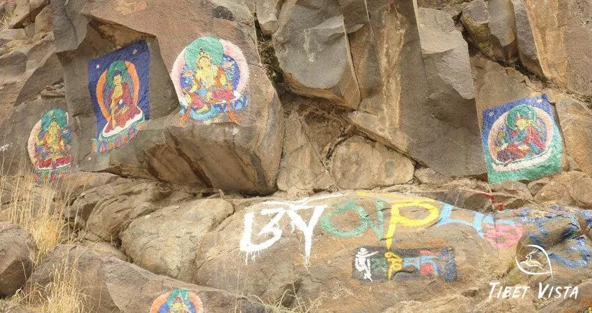 The colorful stone carvings of Buddhas and mantras on the rockface